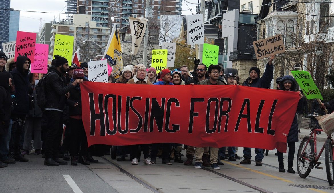 People protesting with signs 'housing for all'